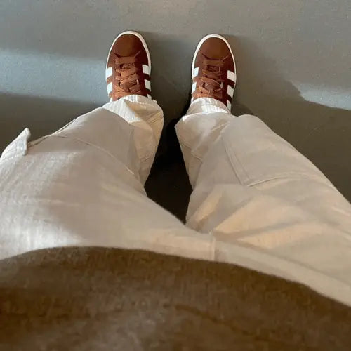 La Adidas Campus 00s Bark porté avec un pantalon cargo blanc cassé et un pull marron.