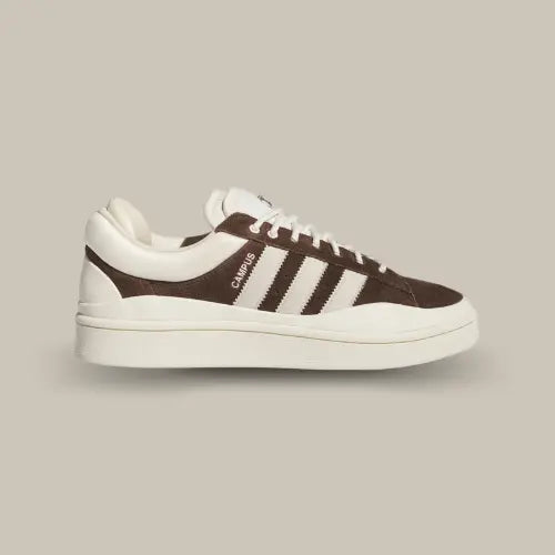 La Adidas Campus Deep Brown Chalk Bad Bunny possède une base en daim marron réhaussée par des superpositions en cuir et TPU blanc. On retrouve une double languette marqué par l'oeil de l'artiste et les trois célèbres bandes de couleur blanche. La semelle en caoutchouc vient finaliser le tout.