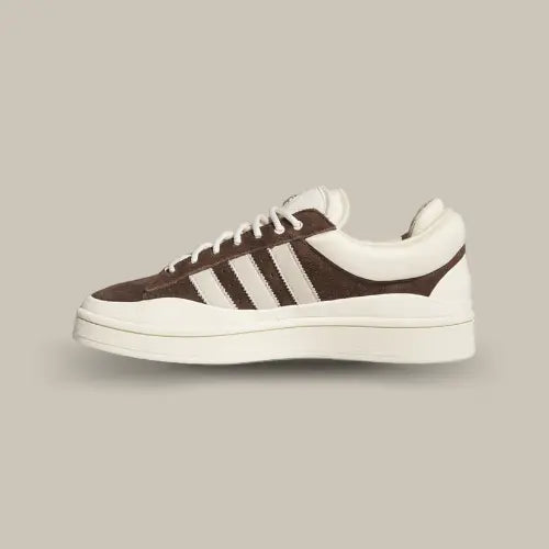 La Adidas Campus Deep Brown Chalk Bad Bunny possède une base en daim marron réhaussée par des superpositions en cuir et TPU blanc. On retrouve une double languette marqué par l'oeil de l'artiste et les trois célèbres bandes de couleur blanche. La semelle en caoutchouc vient finaliser le tout.