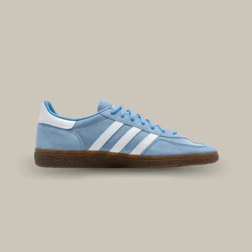 La Adidas Handball Spezial Light Blue de coté avec sa tige en suède bleu clair, ses trois bandes blanches assortis au talon et sa semelle en gomme.
