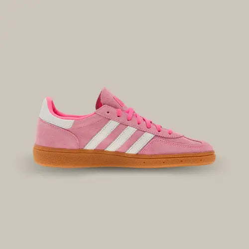 La Adidas Handball Spezial Lucid Pink White vue de côté avec sa base de couleur rose, ses trois bandes blanches accordées au heel tab et sa semelle en gomme de caoutchouc marron.