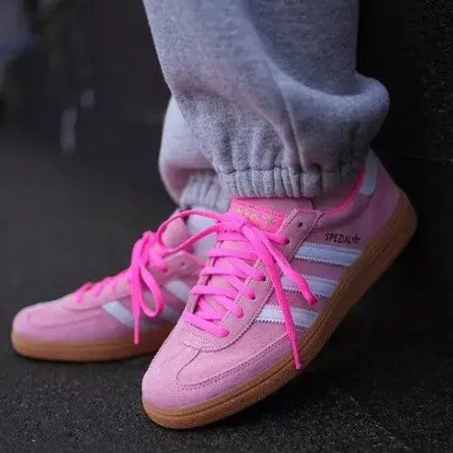 La Adidas Handball Spezial Lucid Pink White portée avec un jogging gris.