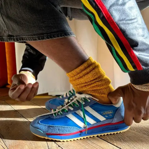 La Adidas SL 72 RS Blue Scarlet portée avec un pantacourt en jean gris et des chaussettes jaunes.