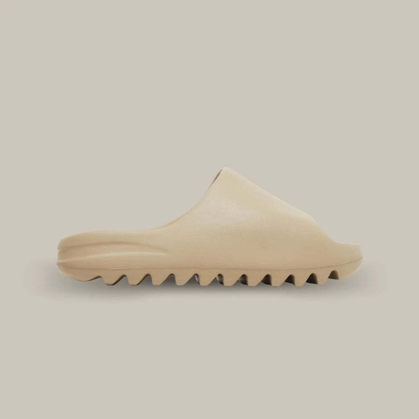 La Yeezy Slide Pure de coté, cette claquette avec son coloris monochrome beige our et sa structure en mousse EVA.