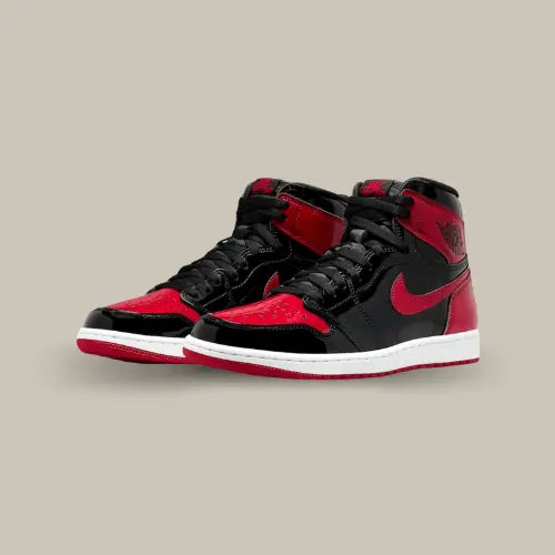 La Air Jordan 1 High OG Patent Bred possède une base en cuir verni premium avec le coloris des Chicago Bulls. On retrouve des empiècements rouge sur le col, le talon, la toebox, le swoosh et l'outsole. Le mot "Family" est brodé sur la doublure inférieure et le Hang Tag Jumpman Metallic Red vient finaliser le design.