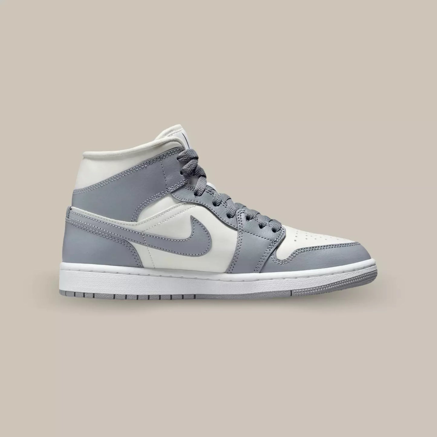 La Air Jordan 1 Mid Grey Sail de coté avec sa base en cuir blanc et ses superpositions en cuir gris.