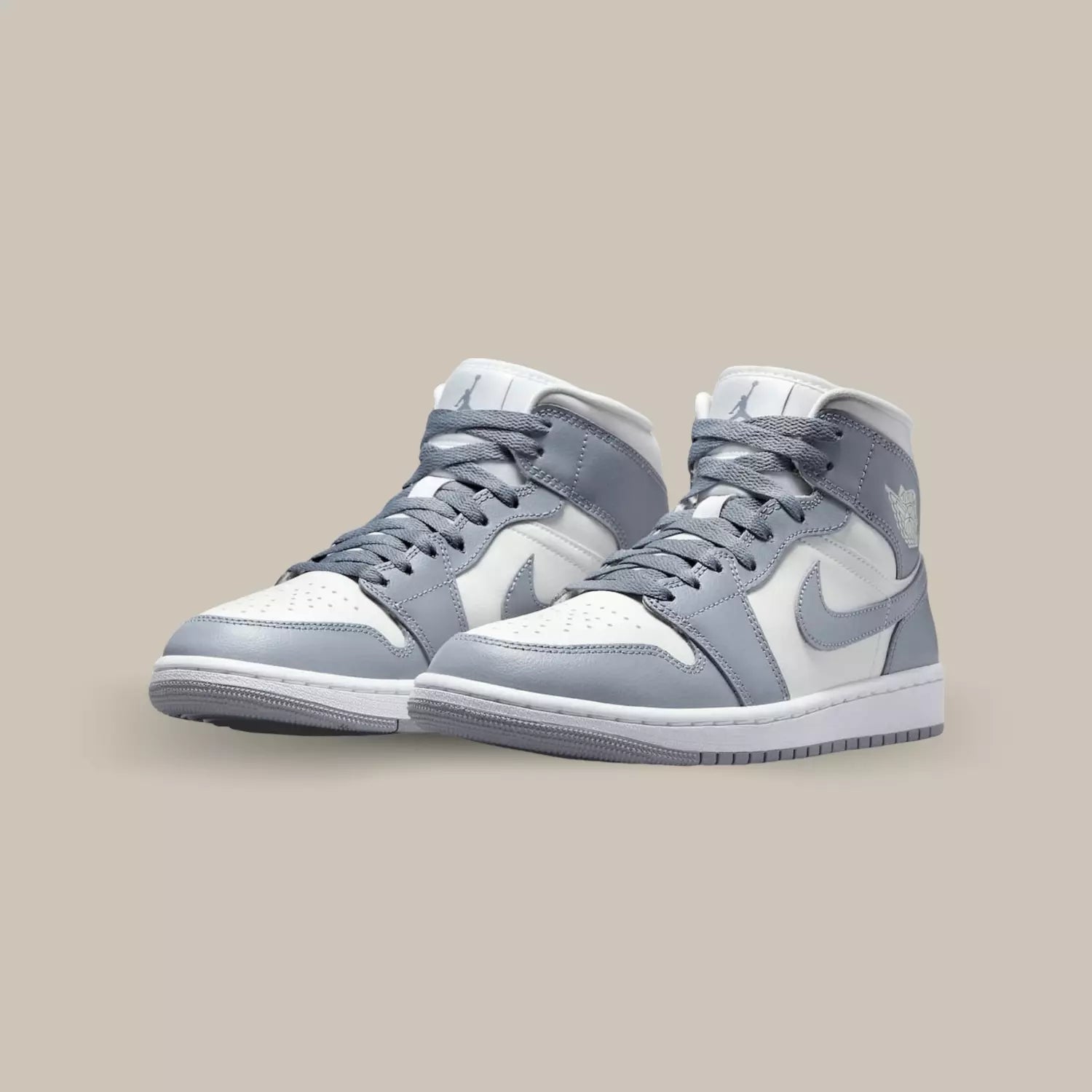 La Air Jordan 1 Mid Grey Sail dévoile une base en cuir blanc cassé, accompagnée de superpositions en cuir gris.