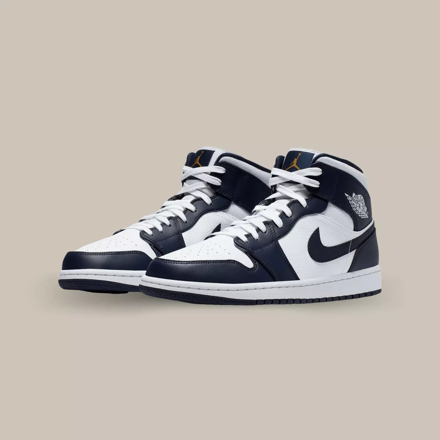 La Air Jordan 1 Mid White Metallic Gold Obsidian affiche une base en cuir blanc sublimée par des superpositions en cuir d’un bleu très foncé, presque noir.