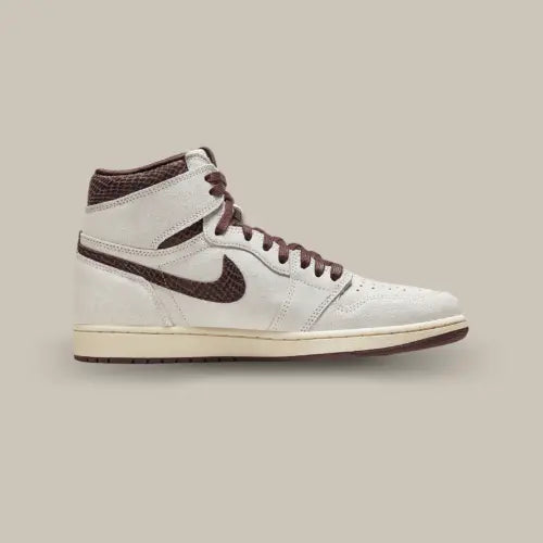 La Air Jordan 1 Retro High OG A Ma Maniére vue de côté avec sa base en cuir suédé blanc cassé et ses empiècements bordeaux en motif snakeskin.