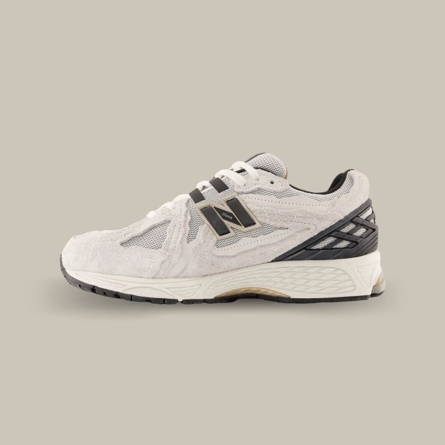 La New Balance 1906R Protection Pack Reflection de coté avec une base en mesh beige accompagnée de superpositions à l’effet déchiré en suède et hairy suède beige.