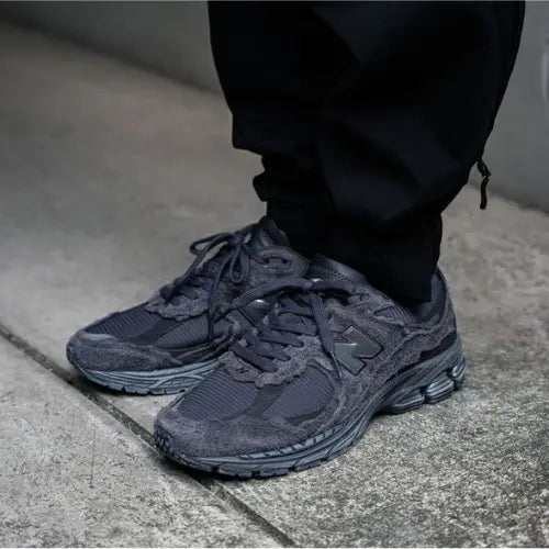 La New Balance 2002R Protection Pack Phantom portée avec un pantalon large noir.