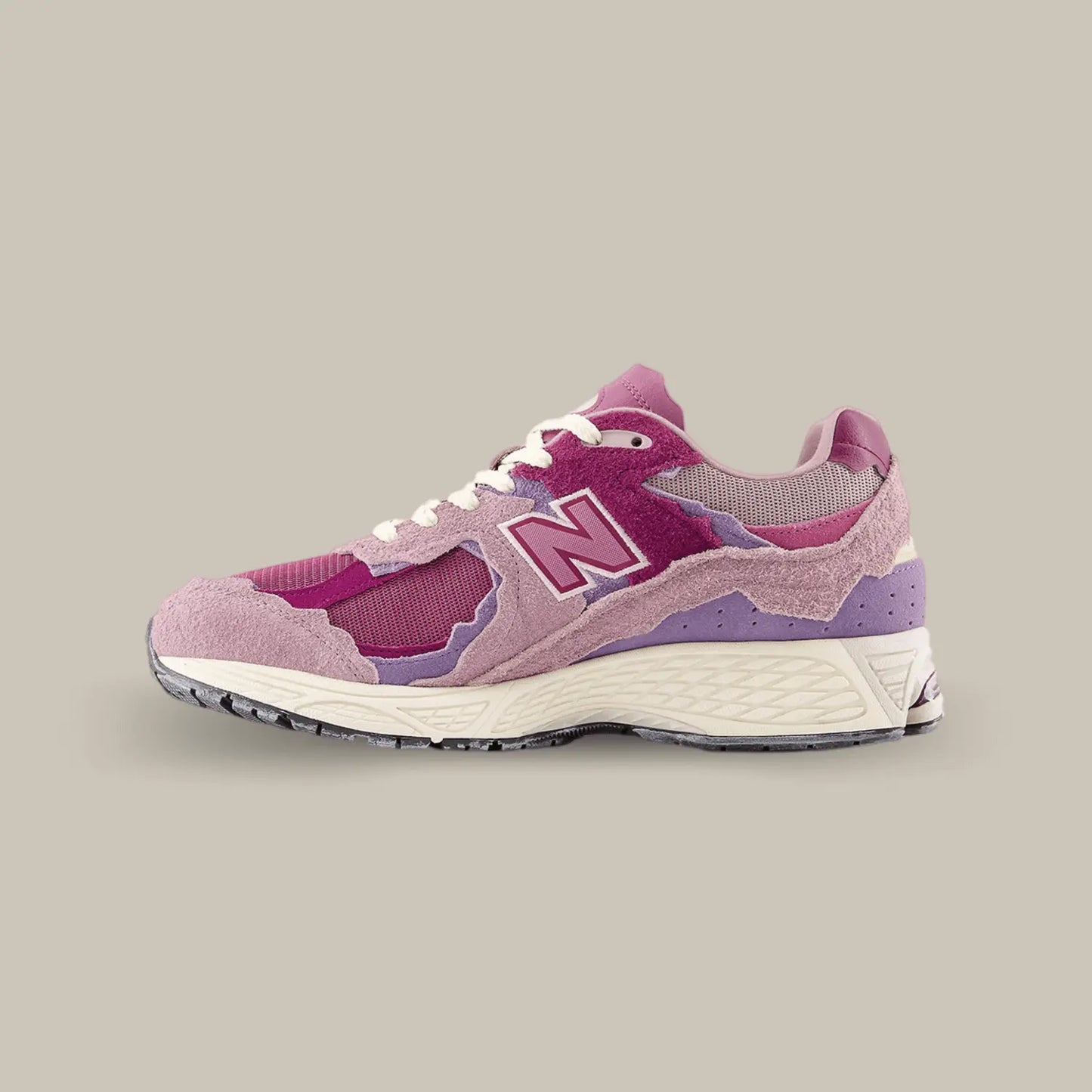 La New Balance 2002R Protection Pack Pink de coté avec une base qui associe mesh, cuir lisse et suède. Cette nouvelle version présente un design penchant vers des coloris rose.