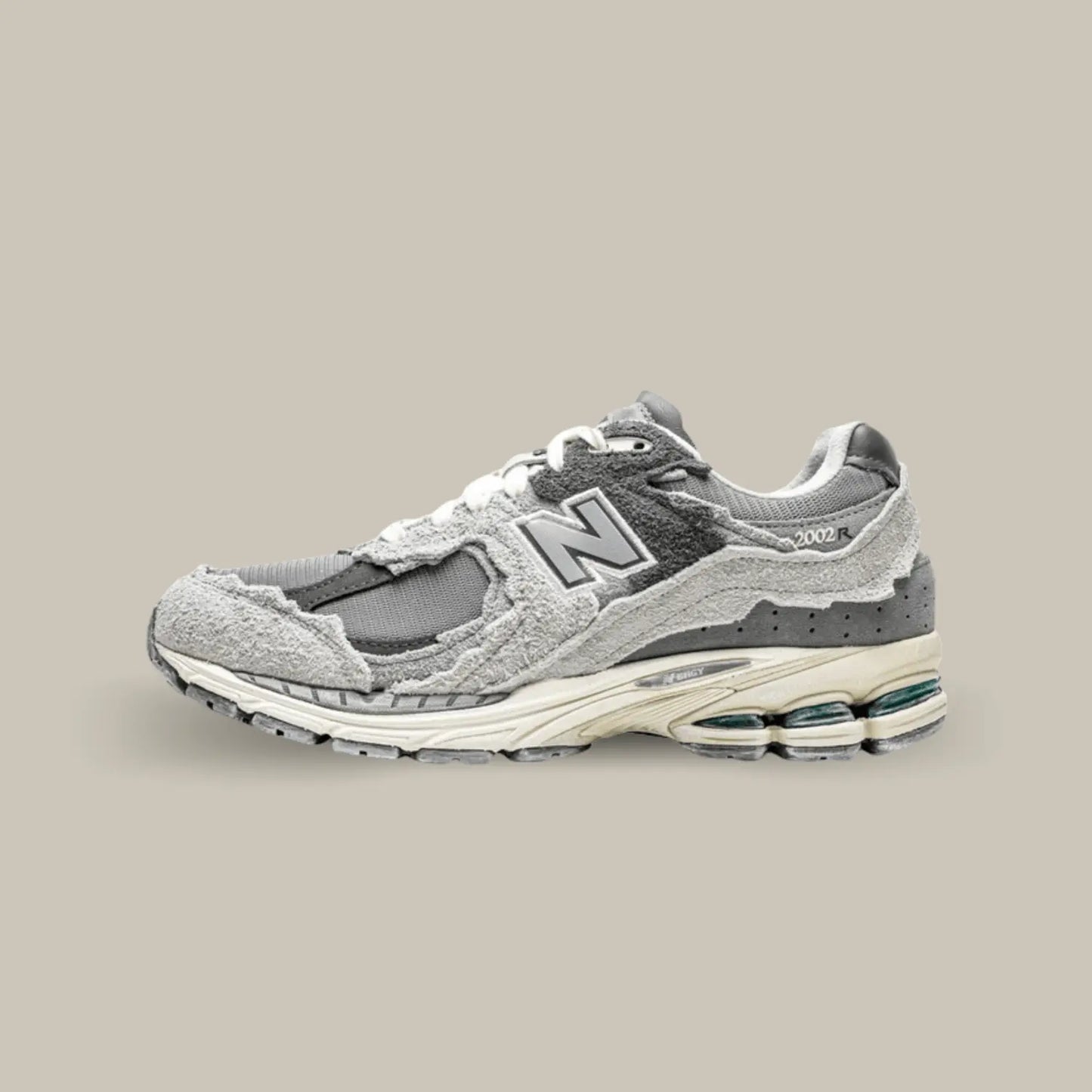 La New Balance 2002R Protection Pack Rain Cloud de coté avec sa base en mesh de couleur gris, noir et des touches subtiles de bleu. On retrouve des superpositions en suède de couleur grise.