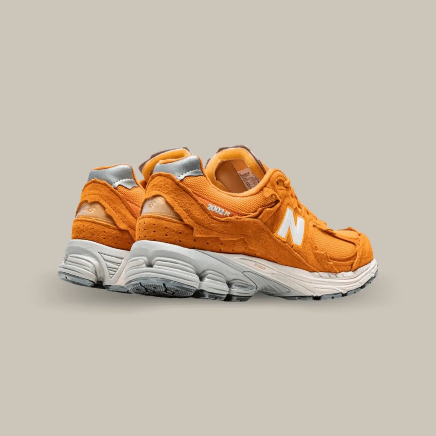 La New Balance 2002R Protection Pack Vintage Orange de dos avec une base en mesh orange et d’un aspect déconstruit. On retrouve du suède sur les superpositions tandis que plusieurs rappels de blanc près du branding et de la midsole offrent un léger contraste à l’ensemble.
