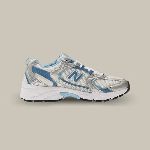La New Balance 530 Metallic Blue vue de côté avec sa base grise et ses empiècements argentés et bleu. On retrouve le logo "N" de couleur bleu et le système ABZORB dans une semelle blanche.