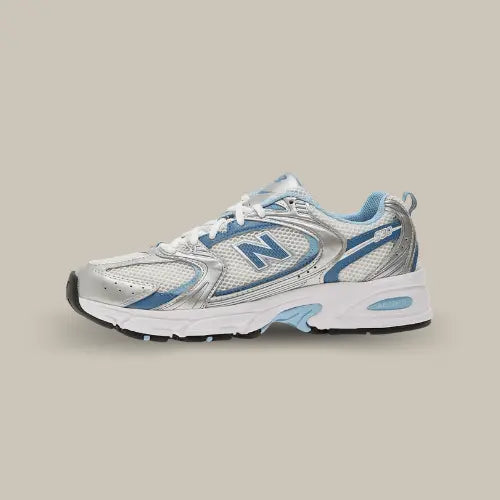 La New Balance 530 Metallic Blue vue de côté avec sa base grise et ses empiècements argentés et bleu. On retrouve le logo "N" de couleur bleu et le système ABZORB dans une semelle blanche.