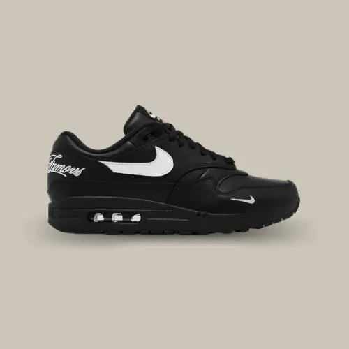 La Nike Air Max 1 '87 SP Supreme Black White vue de côté avec sa base en cuir noir et son swoosh blanc accordé aux écritures sur le talon "World Famous".