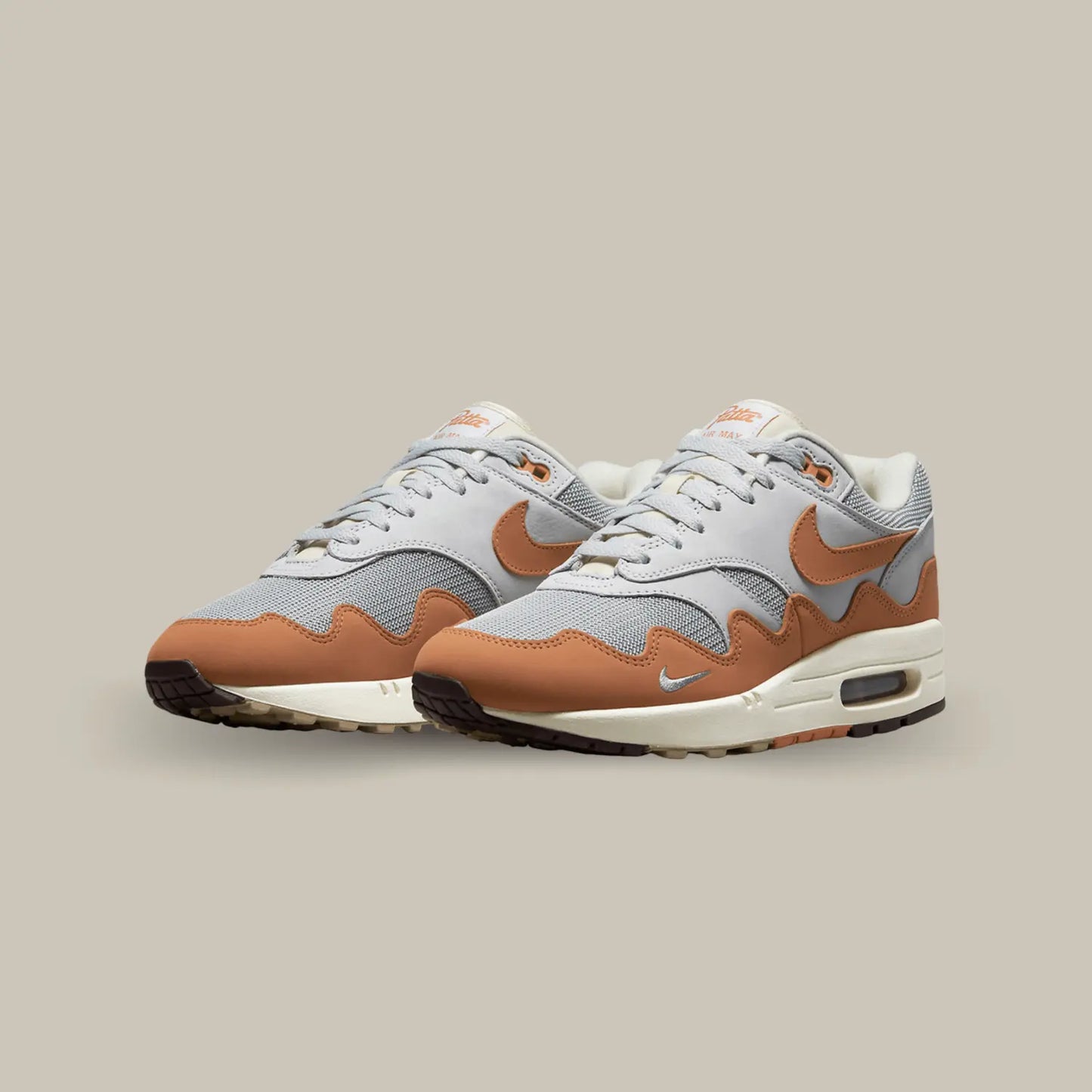 La Nike Air Max 1 Patta « Monarch » affiche une base en mesh gris, couplée à des empiècements en cuir blanc, on retrouve également un swoosh de couleur orange accompagnant les vagues au dessus de la midsole.