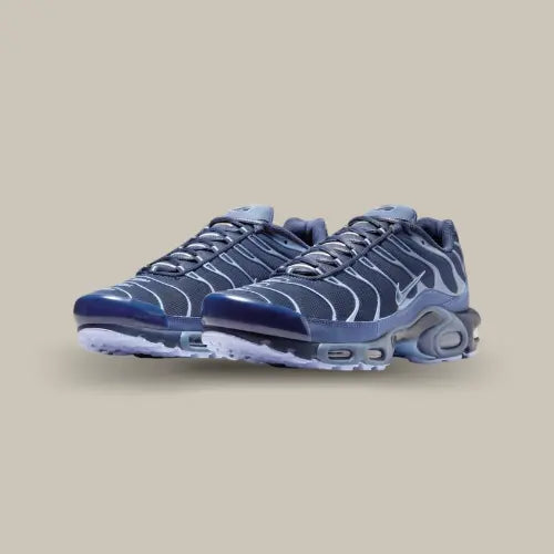 Paire de Nike Air Max Plus Obsidian Aluminum vue de trois quarts avec empeigne Obsidian, lignes ondulées bleu clair et détails brillants.