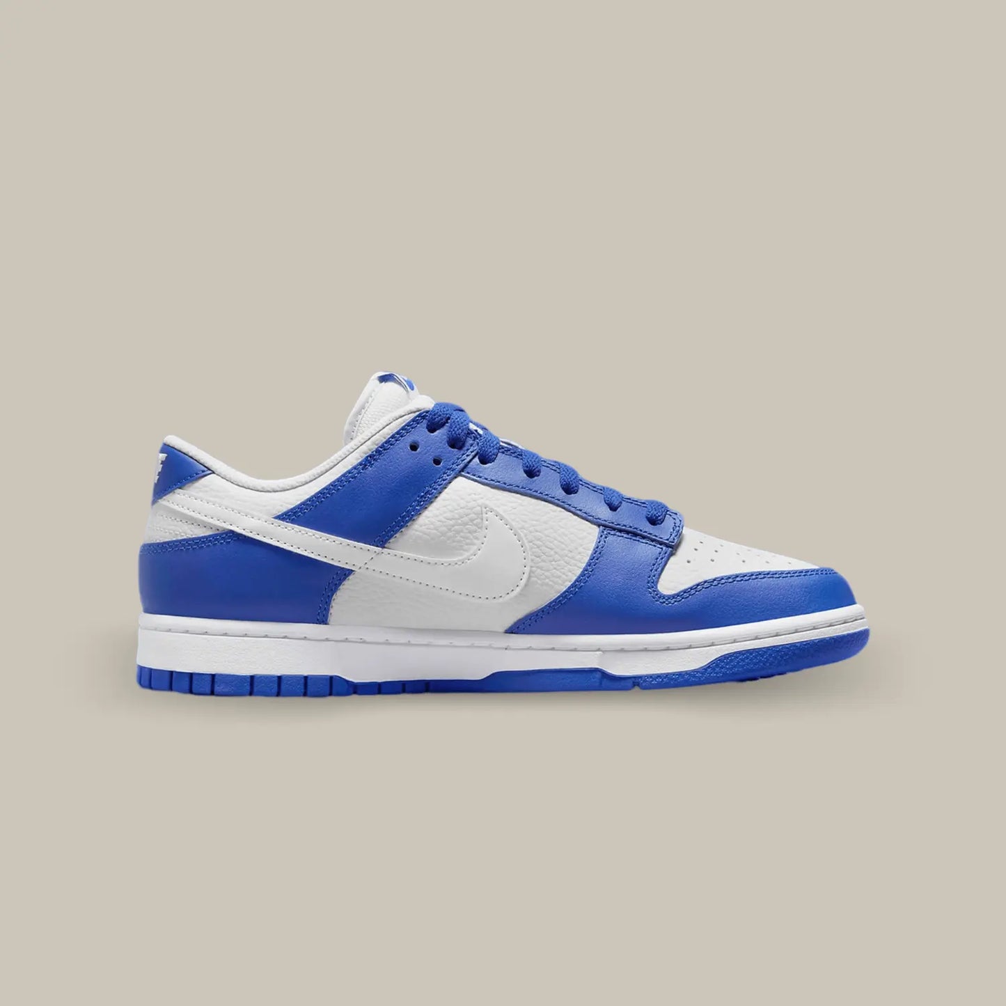 La Nike Dunk Low Kentucky Alternate de coté avec sa base en cuir grainé blanc aux superpositions de cuir bleu royal.
