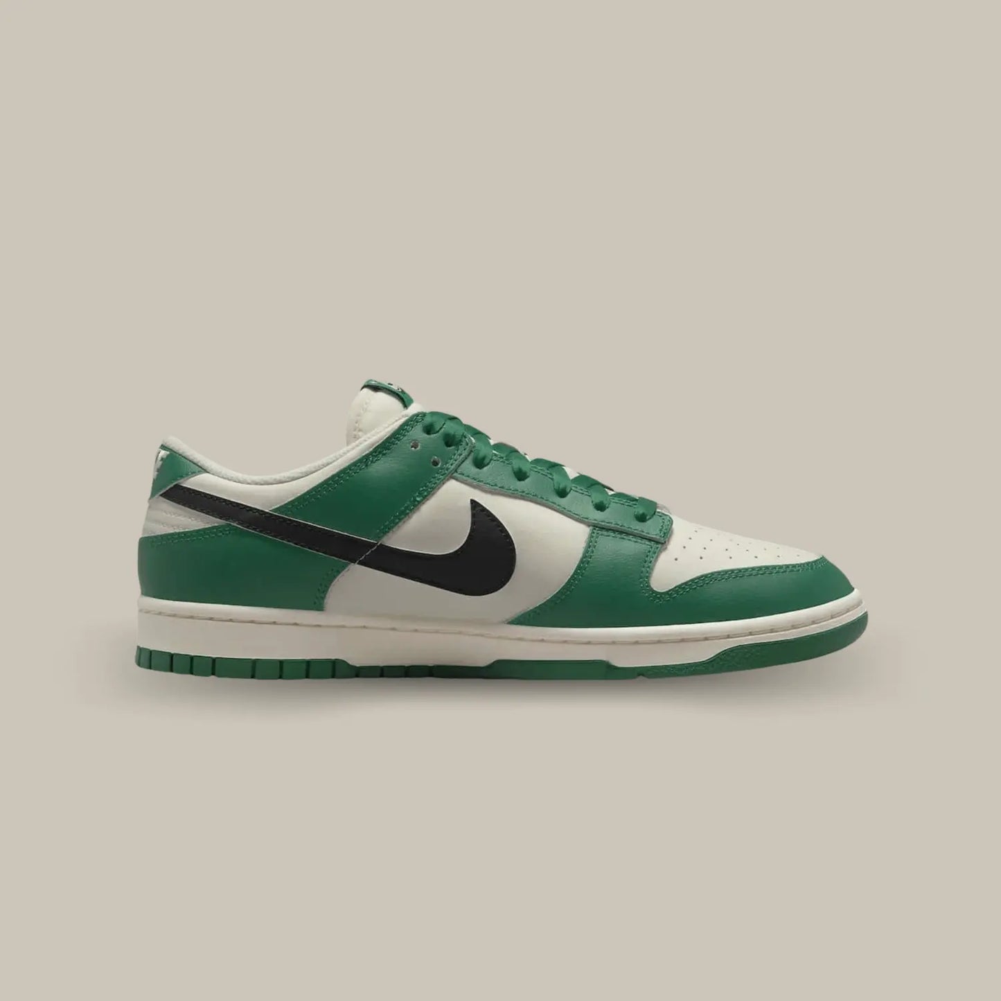 La Nike Dunk Low SE Lottery Green Pale Ivory de coté avec sa base en cuir blanc cassé qui s’accompagne de superpositions en cuir vert bouteille.