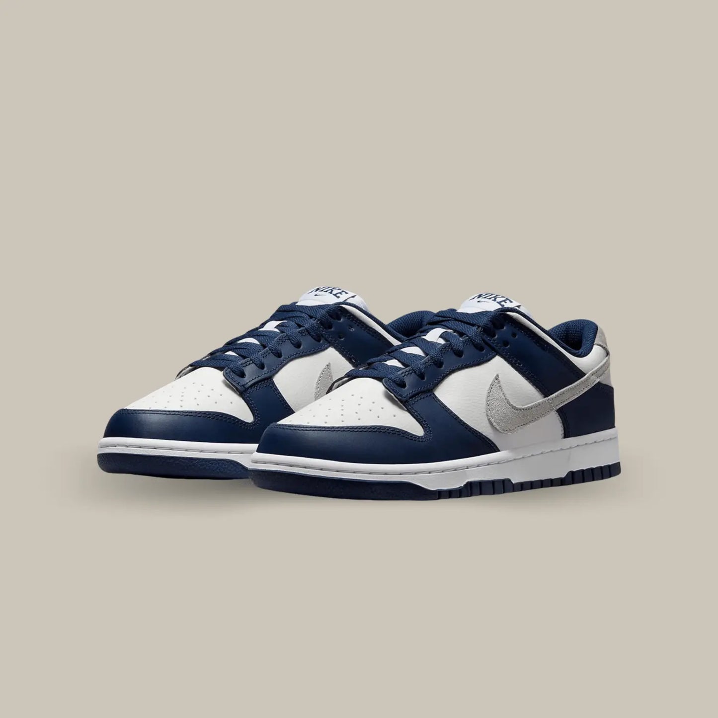 La Nike Dunk Low Summit White Midnight Navy dévoile une base en cuir grainé blanc cassé aux superpositions de cuir bleu marine.
