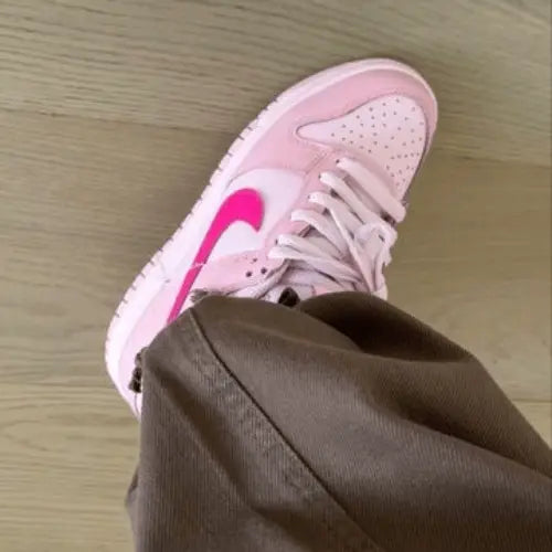 La Nike Dunk Low Triple Pink portée avec un jean large marron.