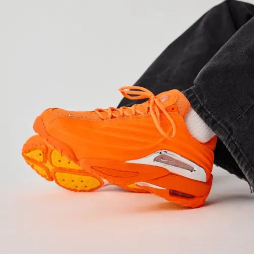 La Nike Hot Step 2 NOCTA Total Orange portée avec un jean noir large.