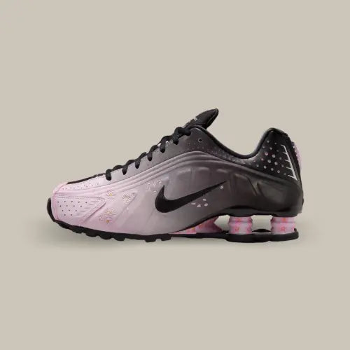 Nike Shox R4 Sakura vue latérale, sneaker noir et rose avec détails floraux inspirés des cerisiers en fleurs et colonnes Shox signature, modèle féminin au design sportif et élégant.