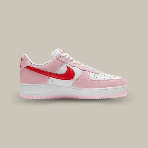 La Nike Air Force 1 Low Love Letter Valentine's Day (2021) de coté avec ses teintes roses et blanche et son swoosh rouge.s