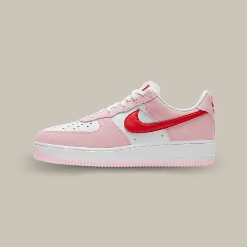 La Nike Air Force 1 Low Love Letter Valentine's Day (2021) de coté avec ses teintes roses et blanche et son swoosh rouge.s