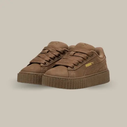 Découvrez la Puma Creeper Phatty Rihanna Fenty Totally Taupe, une sneaker au style audacieux et tendance, née de la collaboration entre Puma et la célèbre artiste Rihanna. Ce modèle incarne l’essence même de la mode urbaine avec sa semelle plateforme signature et son coloris taupe. La tige en cuir premium offre un look élégant et une durabilité optimale, tandis que les finitions dorées, comme le logo Puma, ajoutent une touche de luxe subtil.