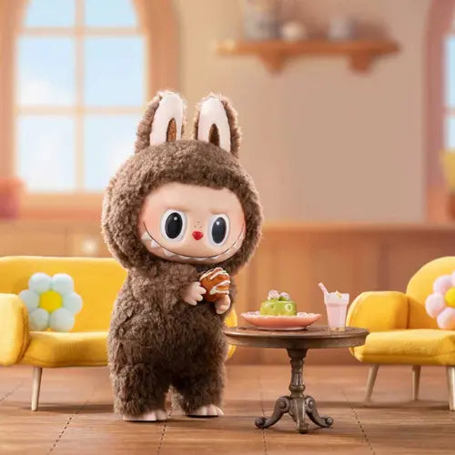 Figurine Pop Mart Labubu Tasty Macarons – modèle Toffee en costume marron, dégustant une pâtisserie dans un décor cosy, série The Monsters.
