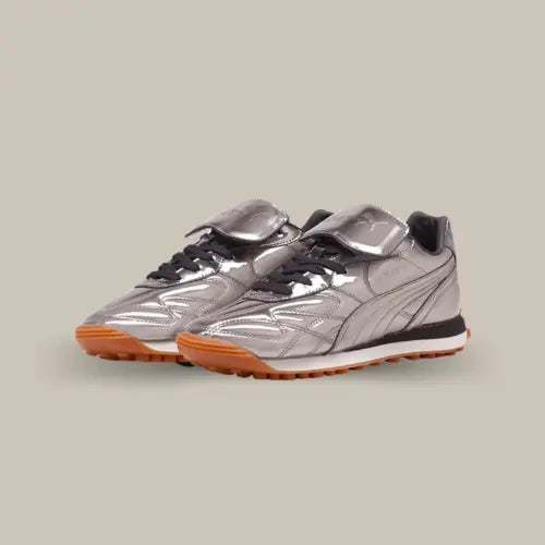 La Puma Avanti C Rihanna Fenty Aged Silver revisite un classique du sportswear avec une touche futuriste et luxueuse. Inspirée de la Puma King, une chaussure de football emblématique, cette version repensée par Rihanna allie design rétro et esthétique moderne. Son cuir métallisé argenté apporte un look avant-gardiste, tandis que la semelle extérieure en gomme assure un confort optimal et une excellente adhérence. La languette oversize, signature de cette collaboration, renforce son allure unique.