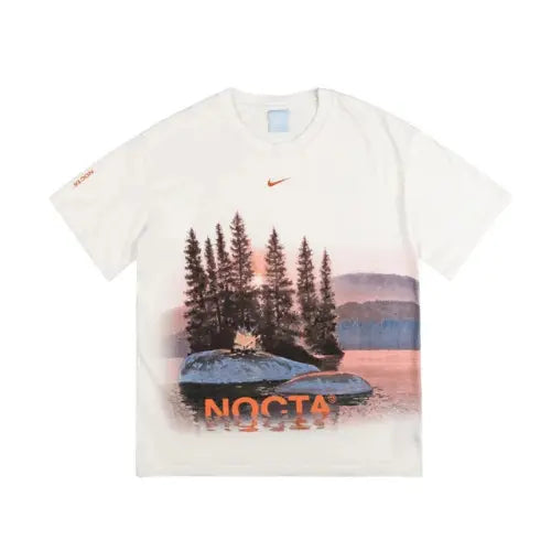 T-shirt Nike x NOCTA Opal Reels White avec imprimé paysage naturel et logo orange NOCTA, collection streetwear inspirée par Drake.