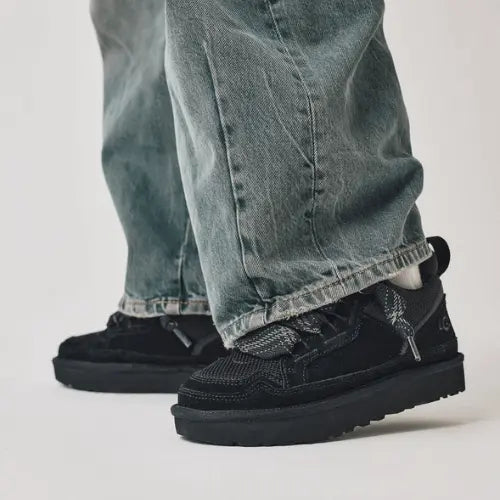 La Ugg Lowmel Black portée avec un jean bleu clair ample.