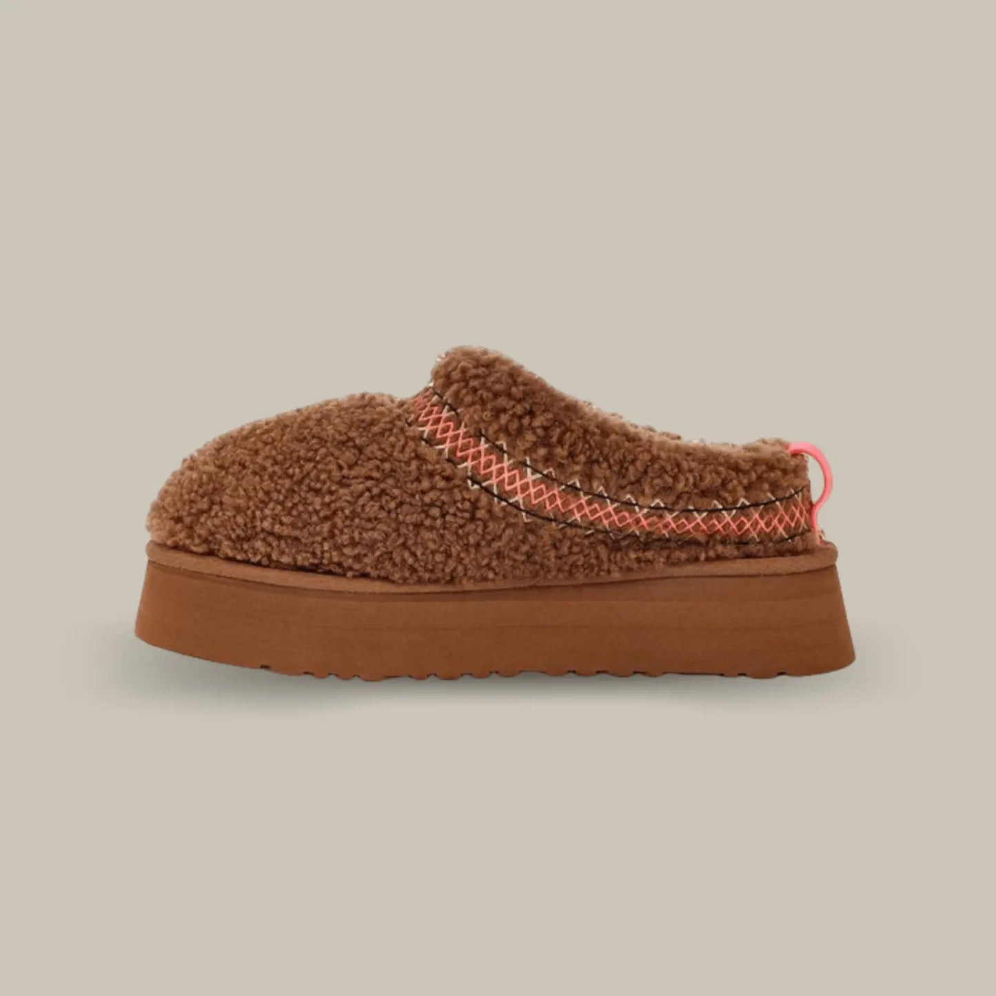 La UGG Tazz Braid Hardwood de coté avec sa tige en duvet marron, son épaisse tresse rouge et noir en polyester recyclé et sa semelle compensée de 4.4cm en EVA.