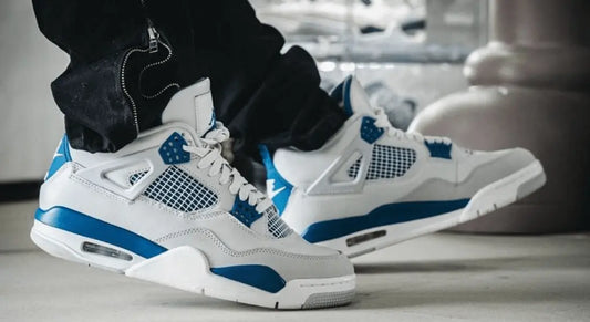 La Air Jordan 4 Retro Military Blue portée avec un pantalon noir.