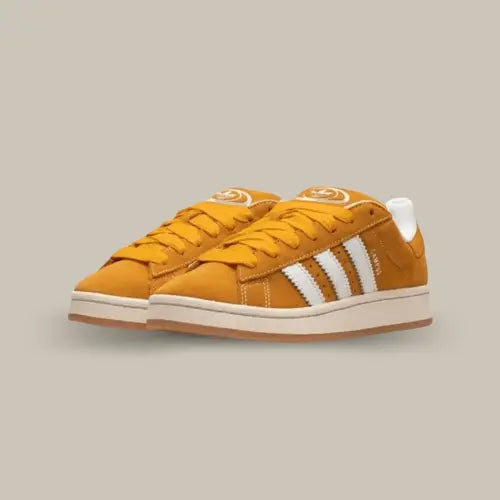 La Adidas Campus 00s Pantone Cloud White possède une base en cuir jaune avec les trois célèbres bandes blanches. On découvre une semelle jaunie pour accentuer l’effet vintage de la paire et une outsole en gomme.