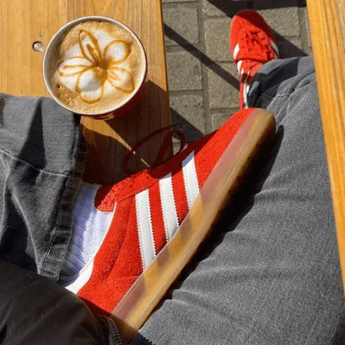 La Adidas Gazelle Indoor Bold Orange porté avec un jean gris à la terrasse d'un café.