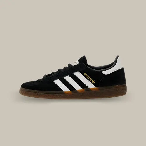 La Adidas Handball Spezial Black Gum de côté avec son daim de couleur noir et ses trois bandes blanches assorties au heel tab.