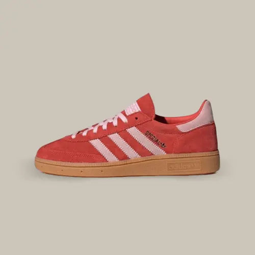 La Adidas Handball Spezial Bright Red Clear Pink vue de coté avec son coloris rouge, ses trois bande roses pale accordé au heel tab. Le logo Spezial est de couleur or et on retrouve la semelle en gomme.