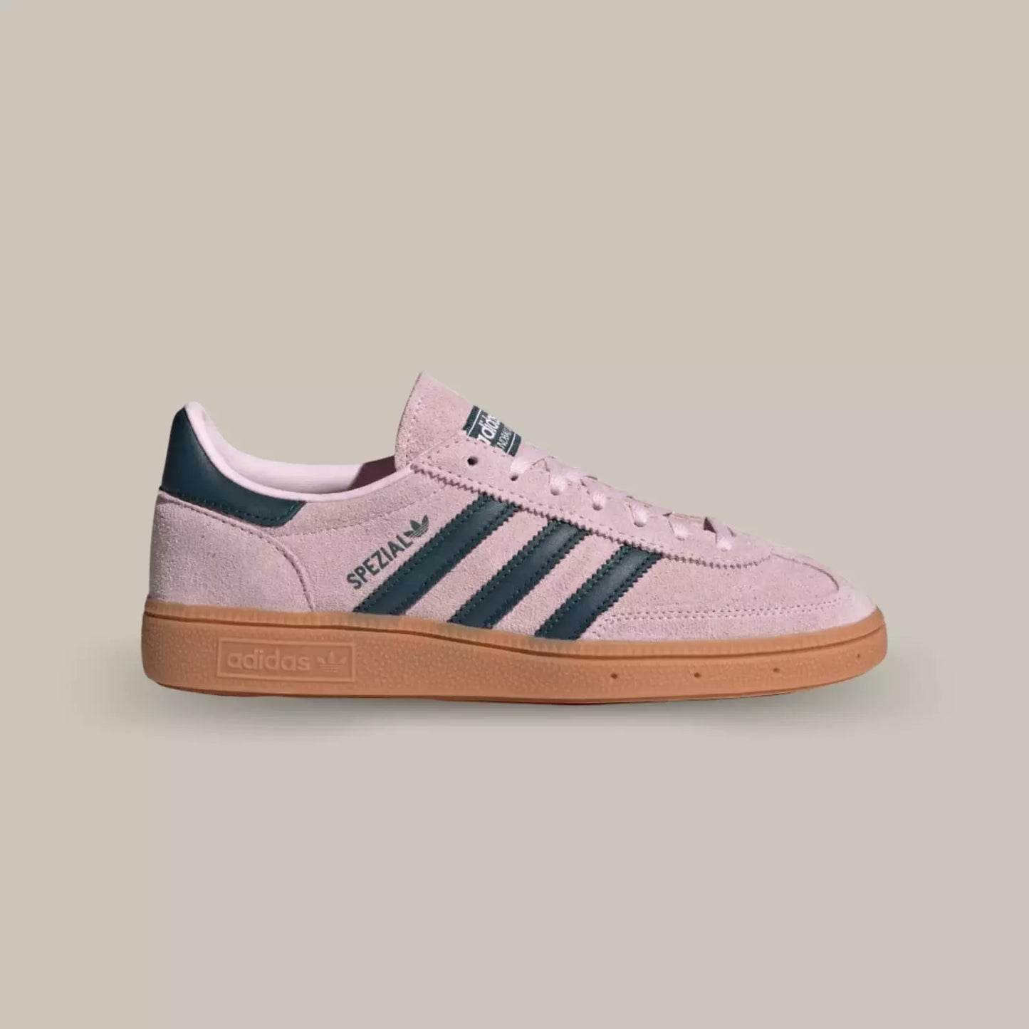 La Adidas Handball Spezial Clear Pink de coté avec sa tige en suède rose clair, ses trois bandes en cuir noir assorti au talon et sa semelle en gomme.