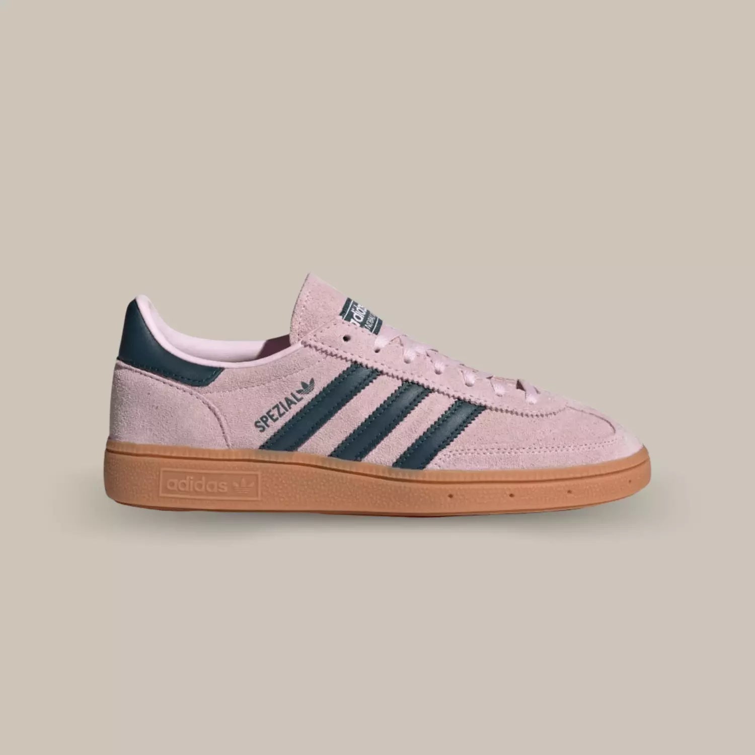 La Adidas Handball Spezial Clear Pink de coté avec sa tige en suède rose clair, ses trois bandes en cuir noir assorti au talon et sa semelle en gomme.