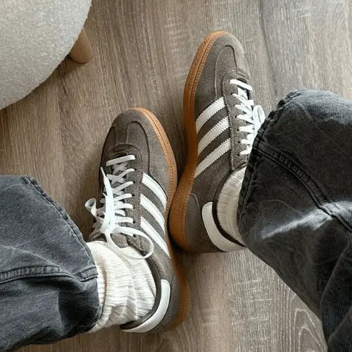 La Adidas Handball Spezial Earth Strata porté avec des chaussettes épaisses blanches et un jean gris foncé.