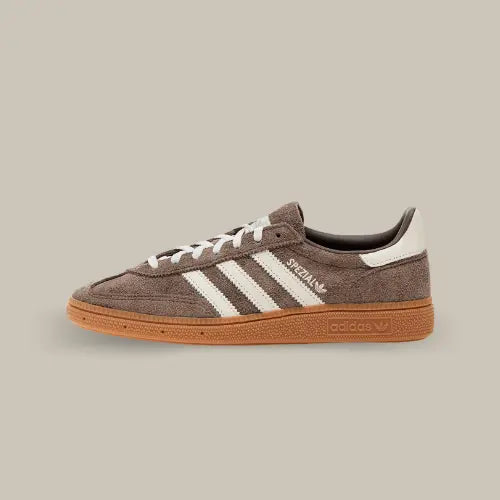 La Adidas Handball Spezial Earth Strata de coté avec son coloris marron et ses trois bandes blanches assorties aux lacets et au heel tab.