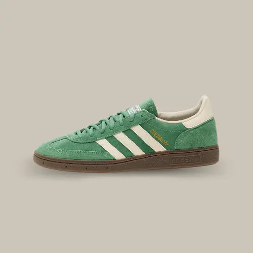 La Adidas Handball Spezial Preloved Green White de côté avec son coloris vert, ses trois bandes blanches accordées au heel tab et sa semelle en gomme de caoutchouc.