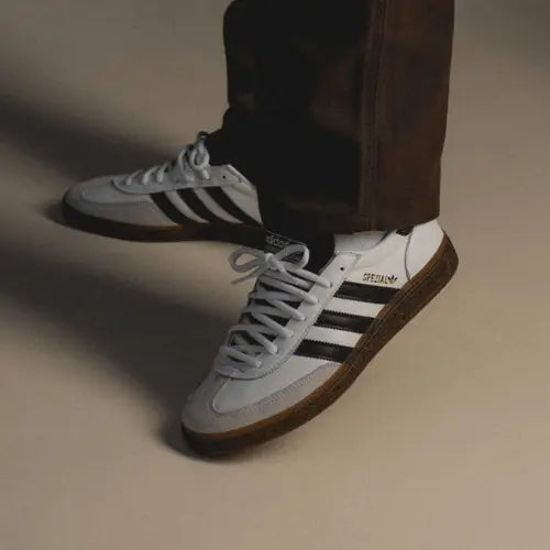 La Adidas Handball Spezial White Black Gum portée avec un pantalon marron.