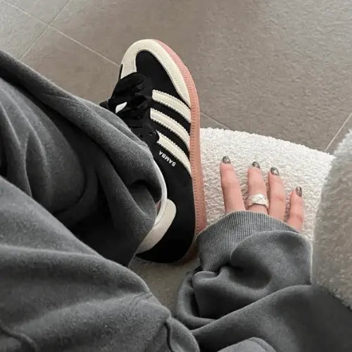 La Adidas Samba OG Black Wonder White portée avec un jogging gris foncé.