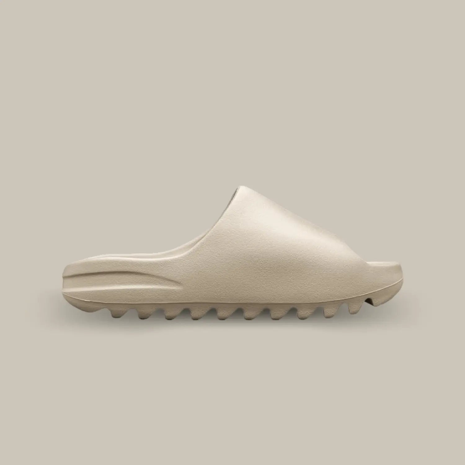 La Yeezy Slide Bone de coté, cette claquette avec son coloris monochrome beige clair et sa structure en mousse EVA.